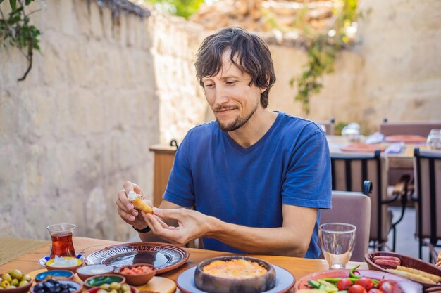 Man eating turkish breakfast turkish breakfast table pastries vegetables greens olives cheeses fried