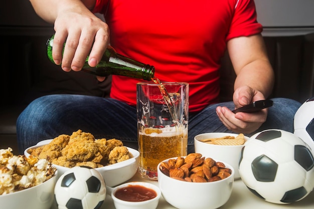 A man eats snacks and drinks beer at home