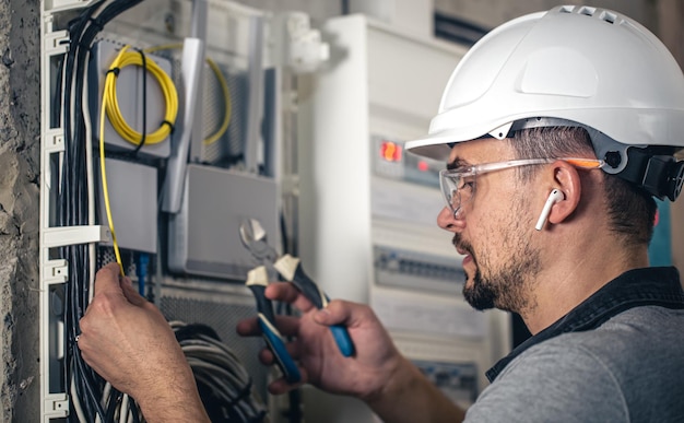 Man an electrical technician working in a switchboard with fuses