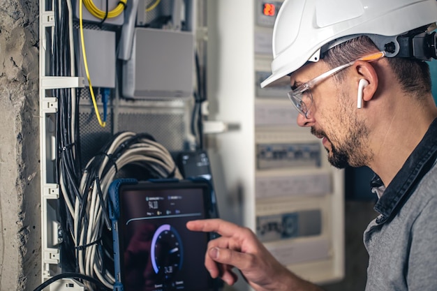 Man an electrical technician working in a switchboard with fuses