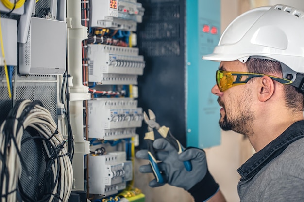 Man an electrical technician working in a switchboard with fuses