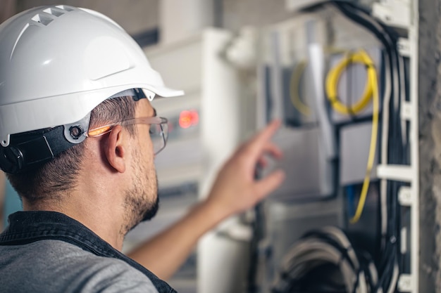 Man an electrical technician working in a switchboard with fuses