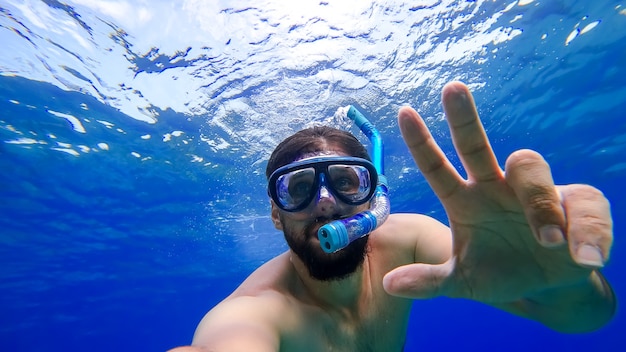 A man engaged in snorkeling is swimming in the underwater kingdom of the red sea trying to surface