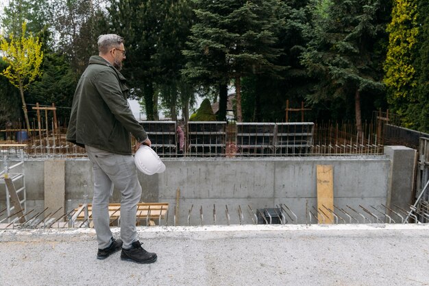 Man engineer standing on construction site looking on workers