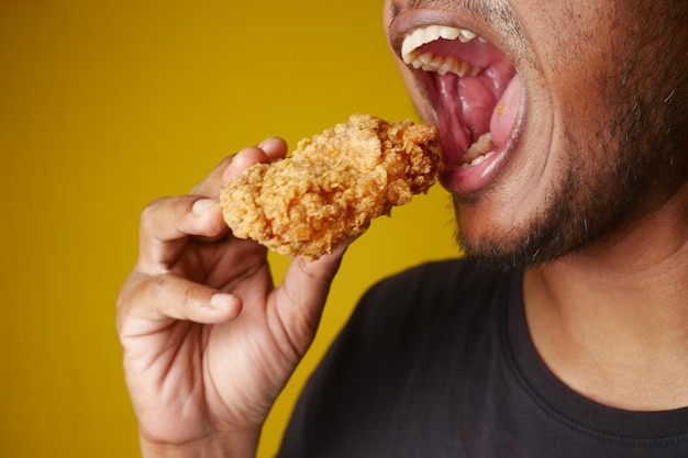 Man enjoying fried chicken mouth open savoring every bite with a big smile