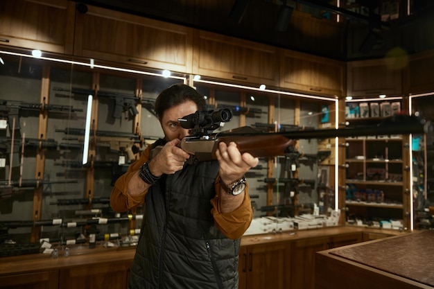 Photo man entrepreneur checking gun aiming telescopic sight at weapon store