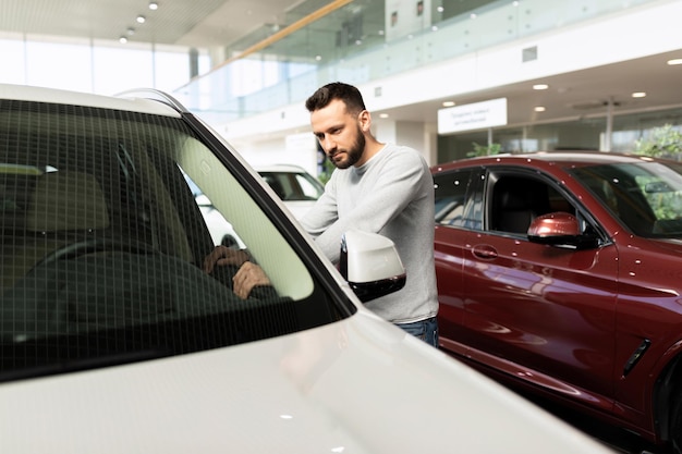 A man examines a car in a car dealership