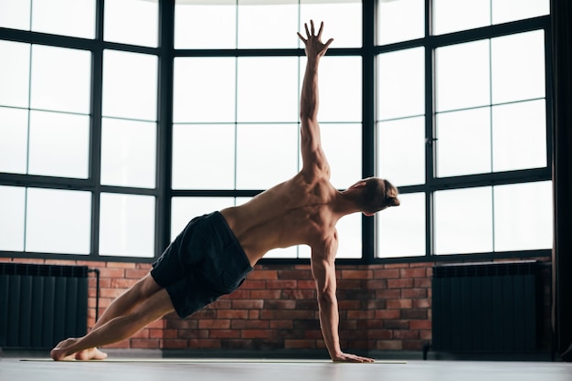 man exercising downward dog asana in gym.