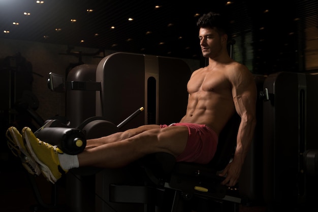 Man Exercising Legs On Machine In Fitness Centar