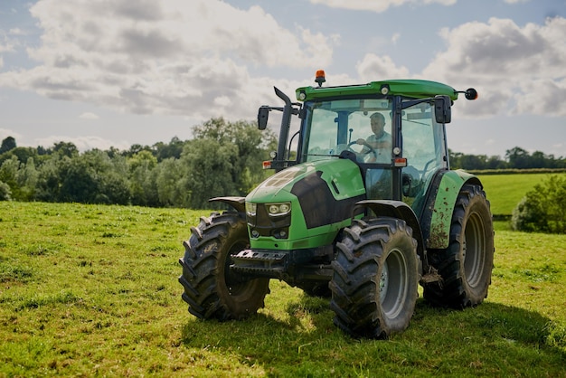 Man farm and green tractor on grass in countryside for agriculture lawn or sustainability in nature Male person or farmer in big agricultural machinery for farming ecology or construction on land