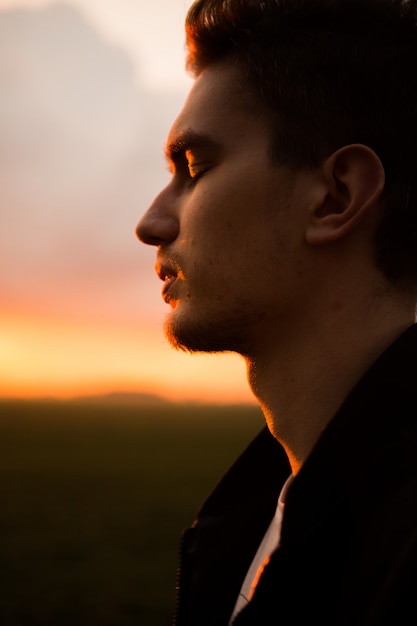 Man in field on beautiful sunset. Silhouette of young man in the nature