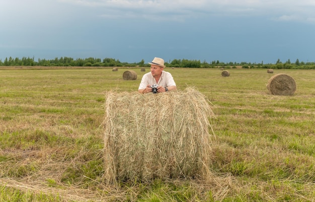 A man in a field with a hay bale in the background