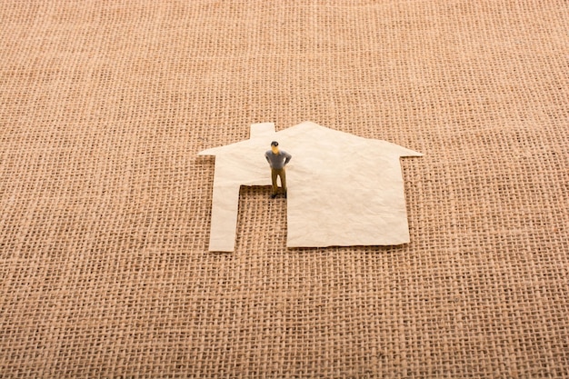 Man figurine and a house shape cut out of paper