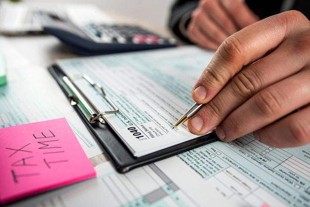 Man filling 1040 blank US tax form at the office Tax for time