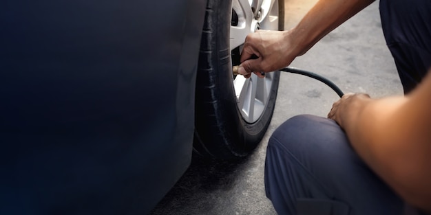 Man filling Air into the Tire. Car Driver Checking Air Pressure and Maintenance