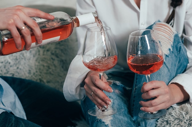 A man fills glasses with rose wine