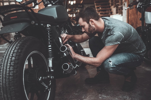 Man fixing bike. Confident young man repairing motorcycle near his garage