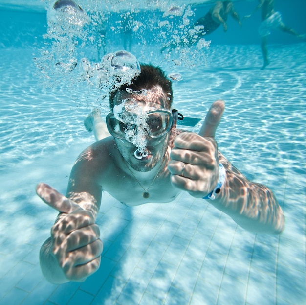 man floats underwater in pool