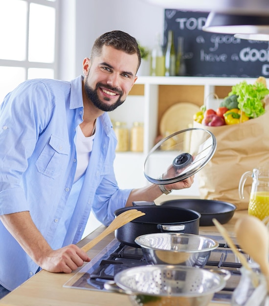 Man following recipe on digital tablet and cooking tasty and healthy food in kitchen at home