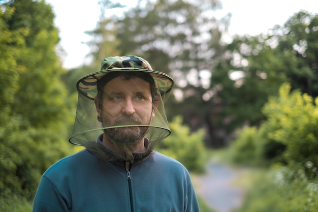 Man in forest with hat with mosquito net