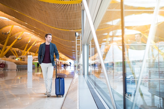 Man front walking at the airport using mobile phone