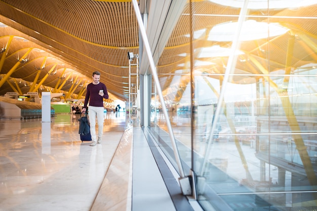 Man front walking at the airport using mobile phone