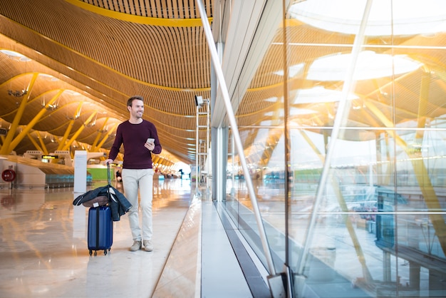 Man front walking at the airport using mobile phone