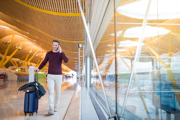 Man front walking at the airport using mobile phone