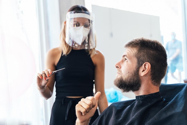 Man gesturing satisfaction with thumb up in a hairdresser