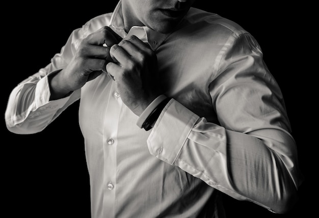 Man getting buttoning up shirt black&white