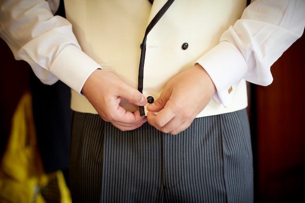 Man getting dressed. Buttoning up his vest