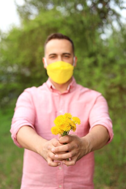 A man giving a bouquet of wild flowers in a medical mask in the presence of allergies