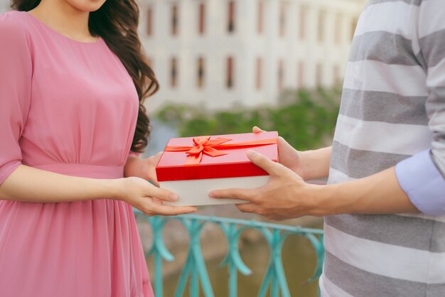 Man giving to his woman a gift. Asian couple in love outdoors