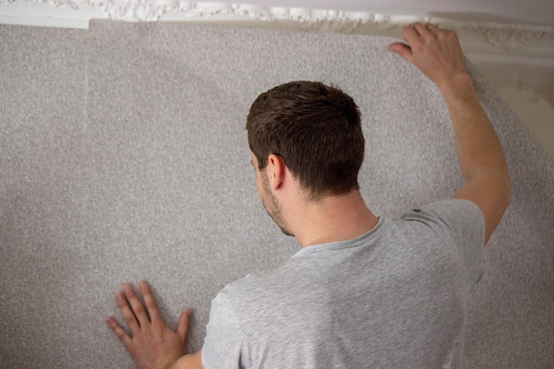 A man glues wallpaper repairs the house