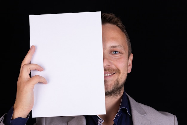 A man in a gray suit holds a blank sheet of paper