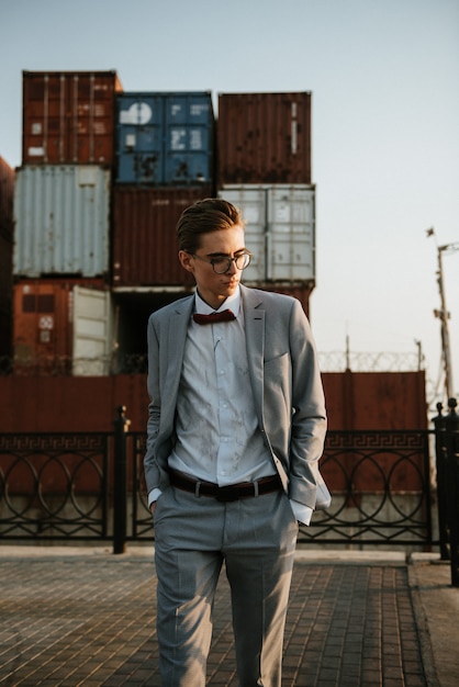 A man in a gray suit poses on the street to advertise men's clothing.