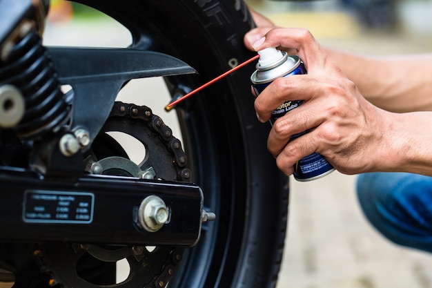 Man greasing motorcycle chain, close up on hand