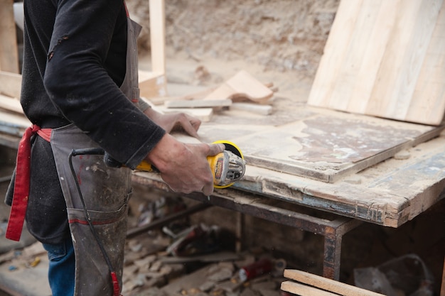 A man grinds wood using a sander carpenter works with a wood