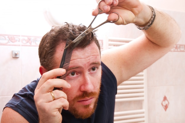 Man grooming his hair with scissors