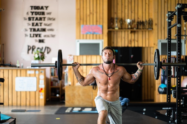 Photo man in a gym doing lunges with weight in a gym