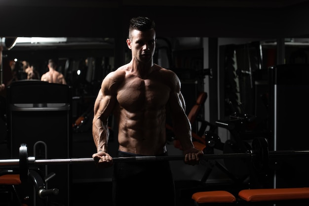 Man In The Gym Exercising Biceps With Barbell