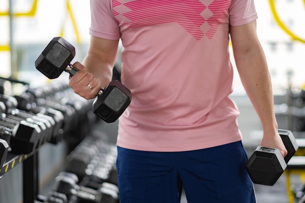 A man in the gym shakes his biceps closeup high quality photo