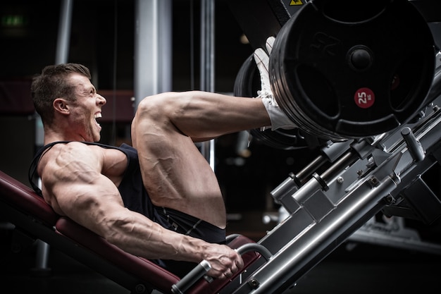 Man in gym training at leg press to define his upper leg muscles