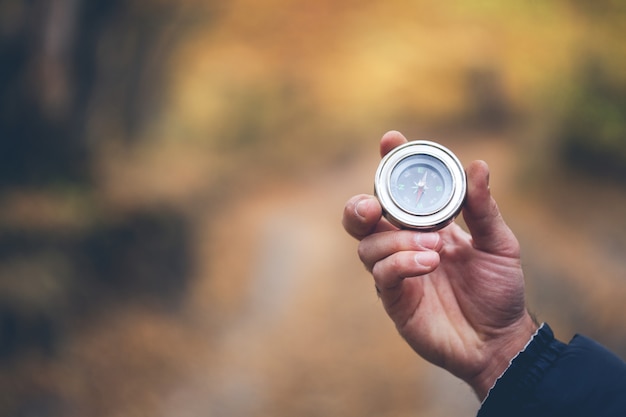 Man hand compass in autumn forest