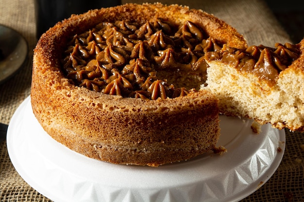 Man hand cutting a slice of typical brazilian churros cake with dulce de leche on a table