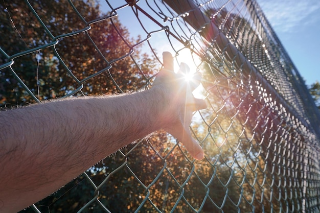 man hand grabbing metallic fence, feeling free