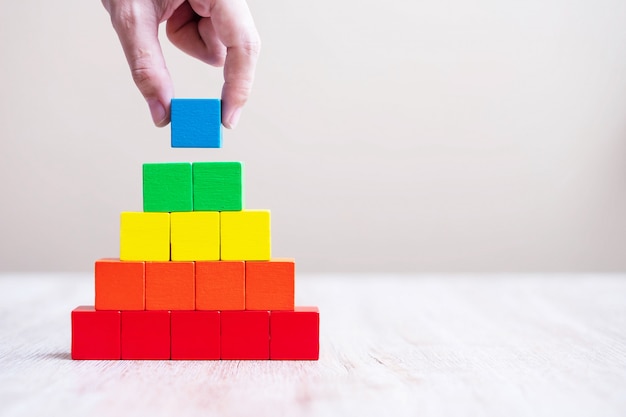 Man hand holding blue color cube block, building a pyramid