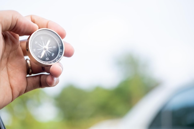 Man hand holding compass on city and car blurred background