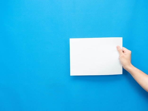 Man hand holding empty sheet on blue background