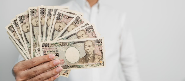 Man hand holding Japanese Yen banknote stack Thousand Yen money Japan cash Tax Recession Economy Inflation Investment finance and shopping payment concepts